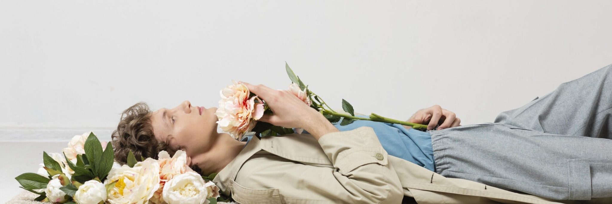 man with trench coat holding flowers scaled e1754224051692.jpg