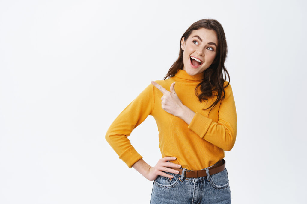 cheerful pretty female model say yes, pointing and looking left at empty space, making decision, standing on white background cheerful pretty female model say yes, pointing and looking left at empty space, making decision, standing on white background